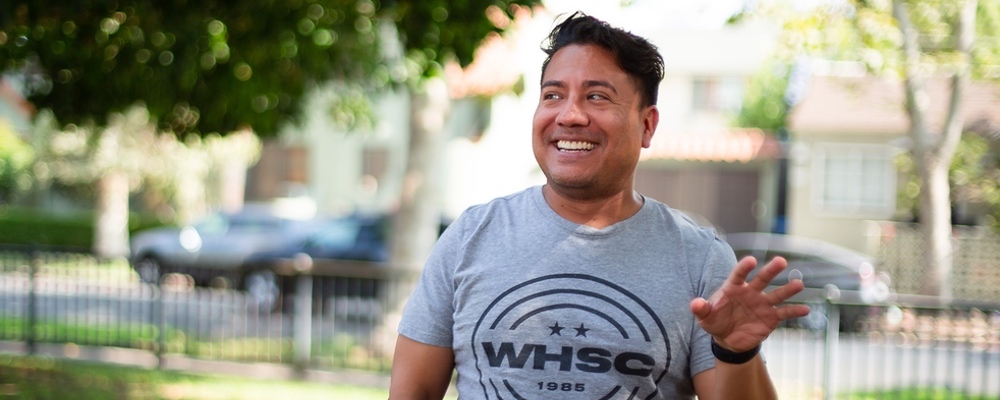 Ken smiles while he speaks, dressed in a West Hollywood Socer club T-shirt.