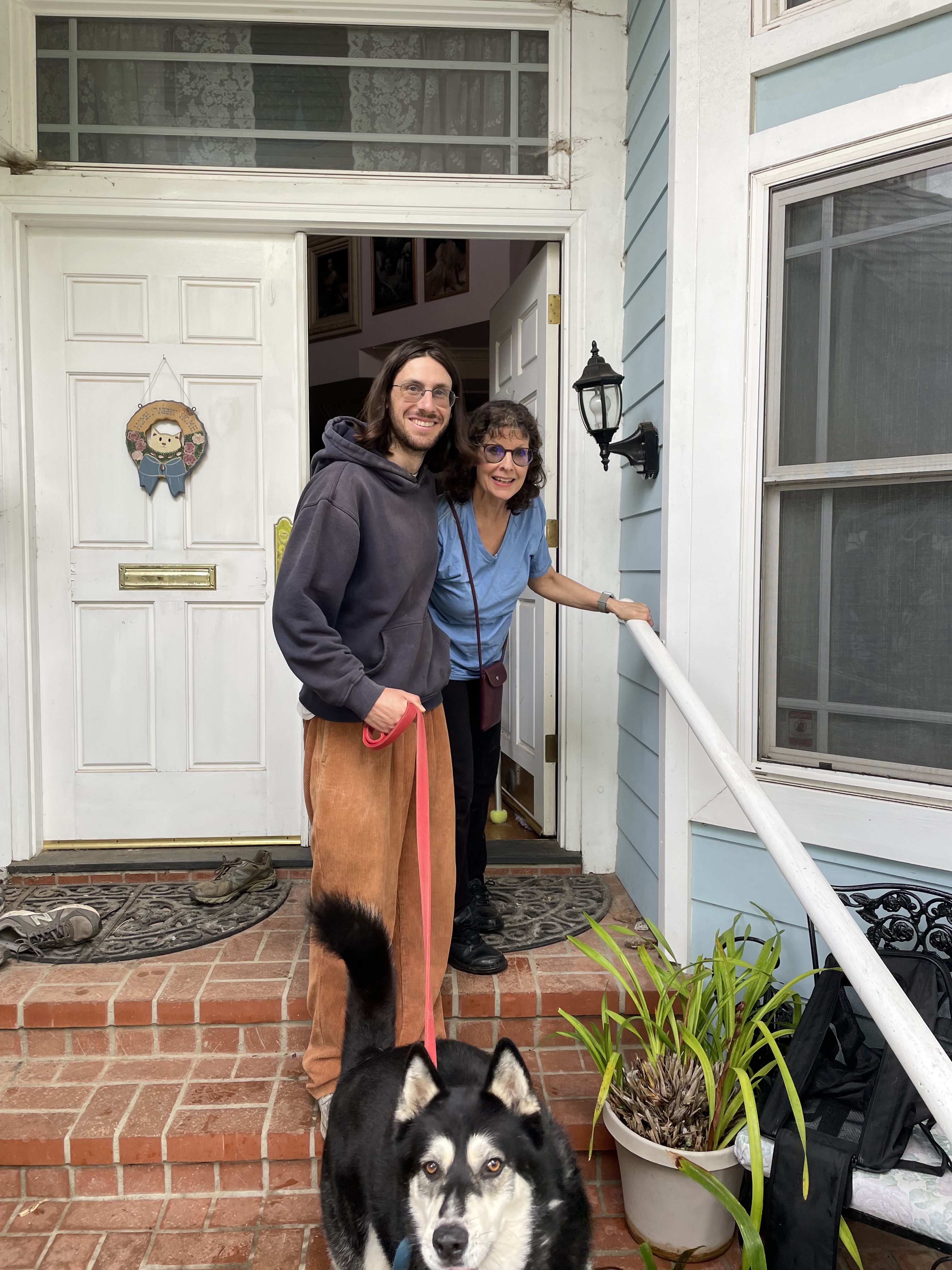 Brian Schlaff and his mom stand outside their Palisades home with their dog 